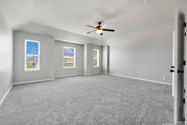 carpeted spare room with a textured ceiling, lofted ceiling, ceiling fan, and a wealth of natural light