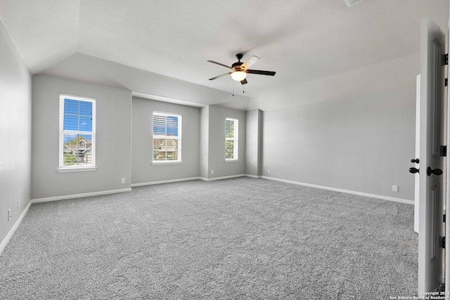 carpeted spare room featuring baseboards, a ceiling fan, and lofted ceiling