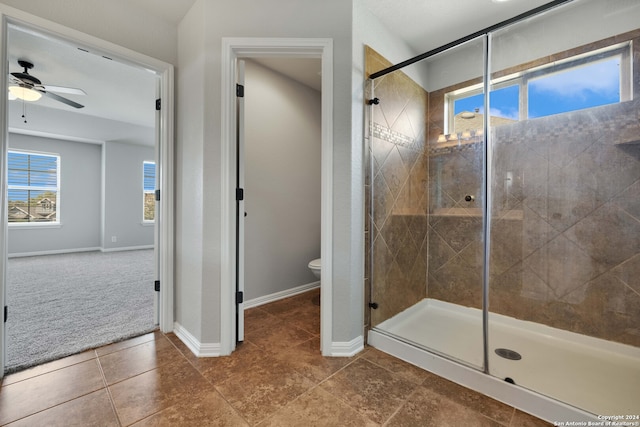 bathroom with tile patterned floors, ceiling fan, a shower with shower door, and toilet