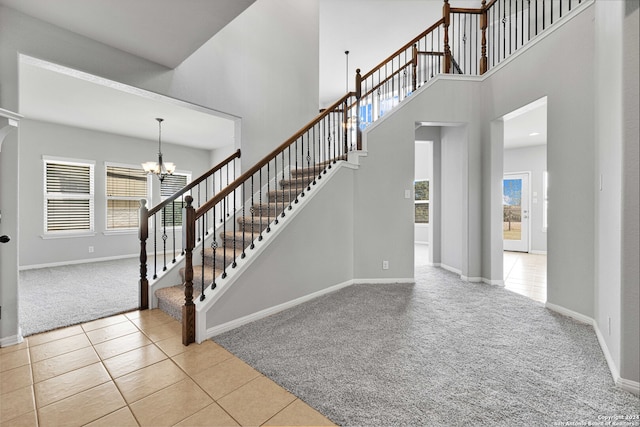 staircase featuring a notable chandelier, a towering ceiling, and carpet floors