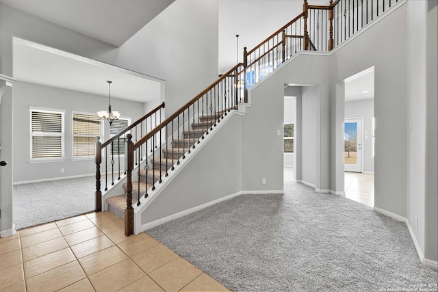 stairs featuring baseboards, a notable chandelier, a high ceiling, carpet, and tile patterned flooring