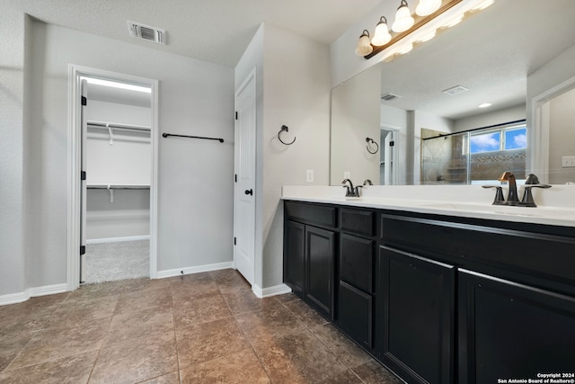 bathroom featuring a textured ceiling, vanity, tile patterned floors, and a shower with shower door