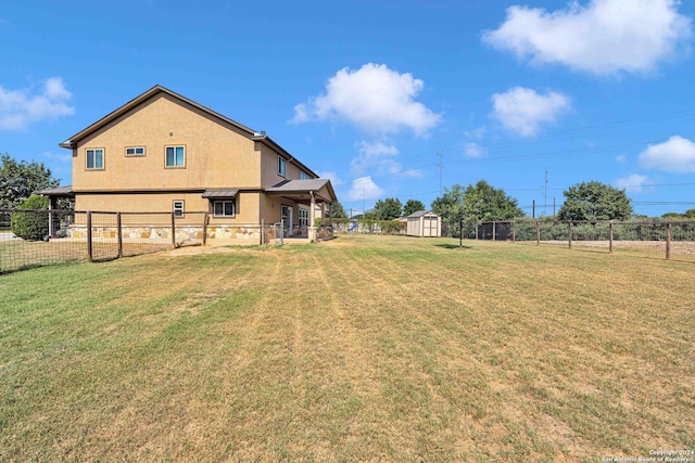 view of yard featuring a storage shed, a fenced backyard, and an outbuilding