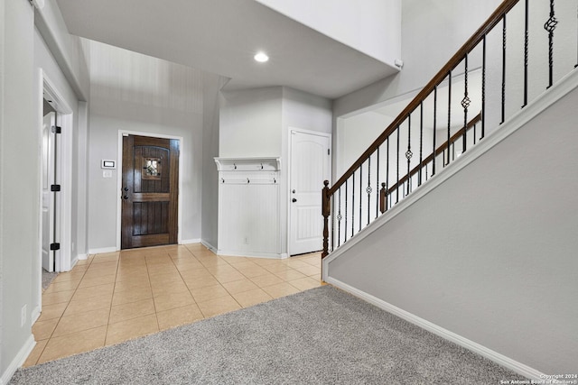 foyer featuring baseboards, recessed lighting, tile patterned flooring, stairs, and carpet