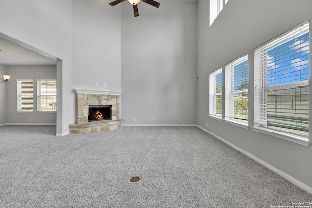 unfurnished living room featuring baseboards, carpet flooring, ceiling fan, and a fireplace