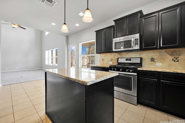 kitchen featuring appliances with stainless steel finishes, decorative backsplash, a kitchen island, light tile patterned floors, and pendant lighting