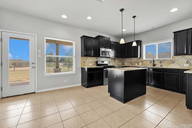 kitchen featuring stainless steel appliances, hanging light fixtures, decorative backsplash, and a kitchen island