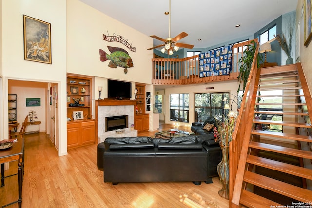 living room featuring ceiling fan, a towering ceiling, and light hardwood / wood-style floors