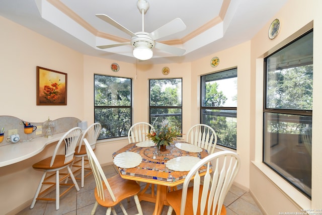 tiled dining room with a raised ceiling, crown molding, and ceiling fan