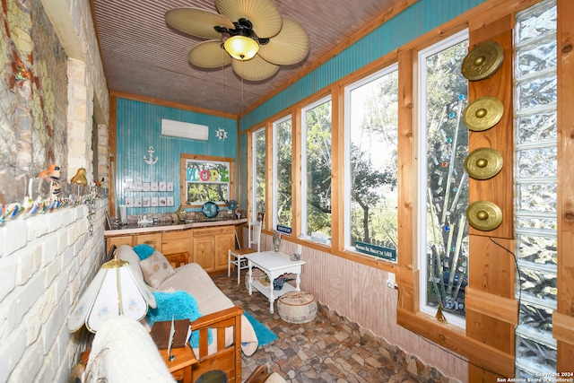 sunroom featuring a wall unit AC and ceiling fan