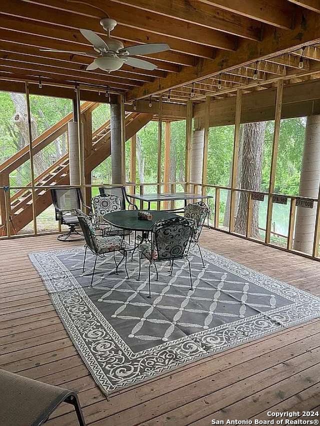 sunroom / solarium with beamed ceiling, ceiling fan, and a wealth of natural light