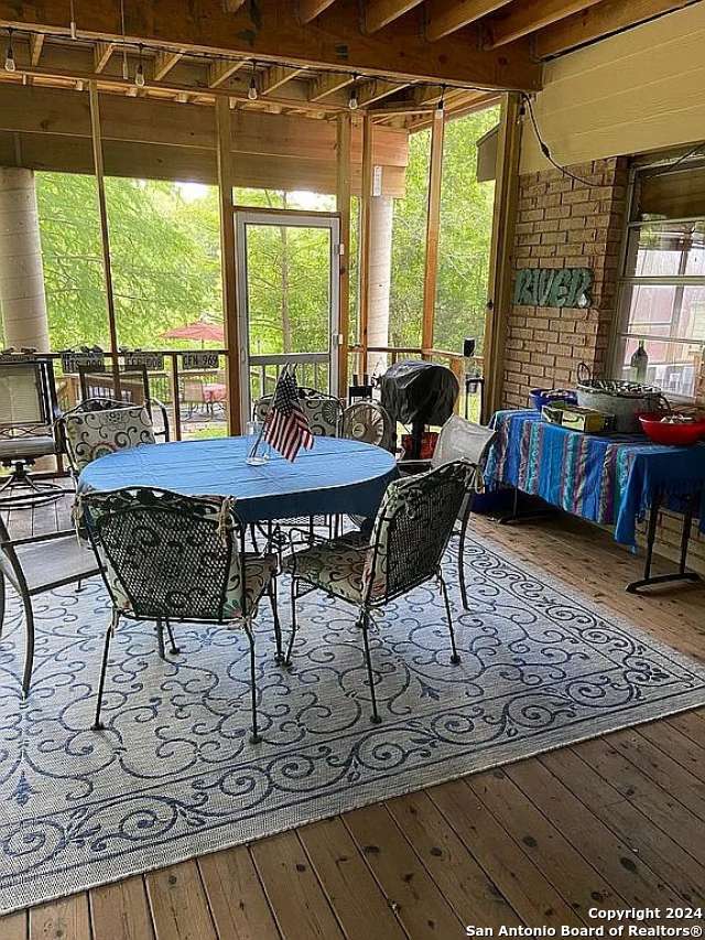 dining space with wood-type flooring, beamed ceiling, and plenty of natural light