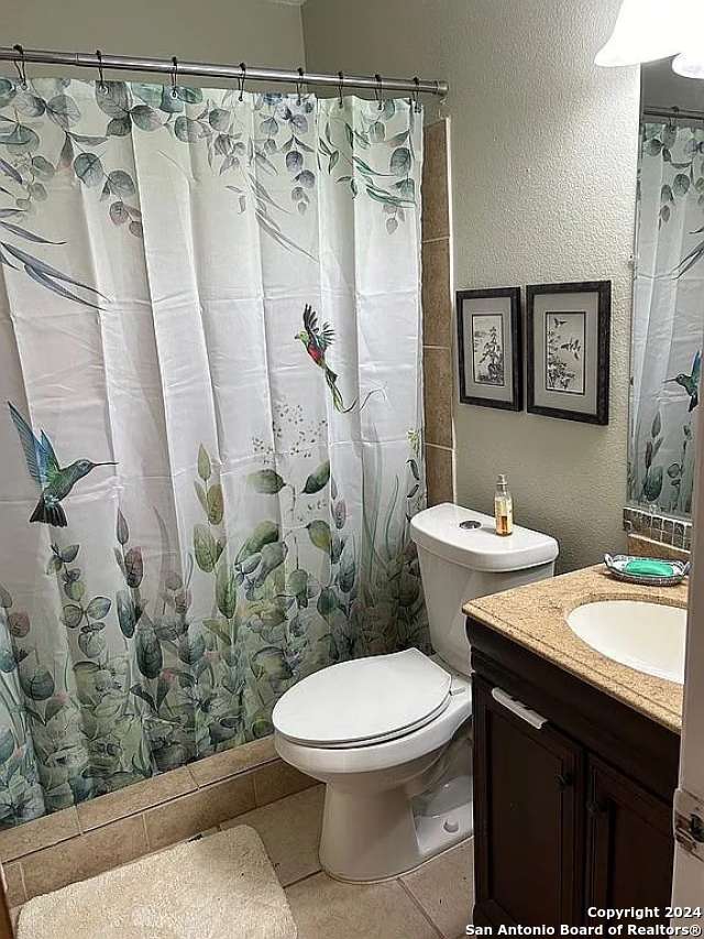 bathroom featuring tile patterned floors, a shower with curtain, vanity, and toilet