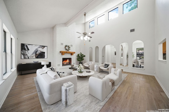 living room featuring light hardwood / wood-style floors, a fireplace, high vaulted ceiling, and a wealth of natural light