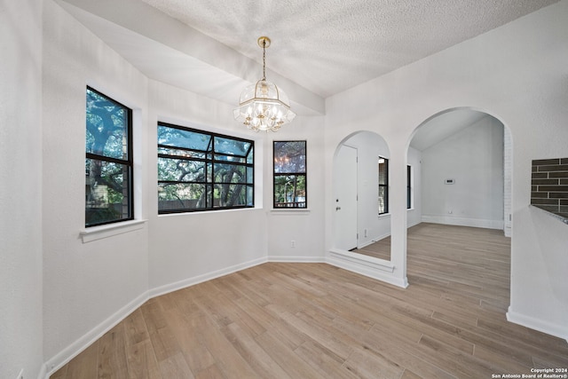 spare room featuring a chandelier, light hardwood / wood-style floors, and a textured ceiling