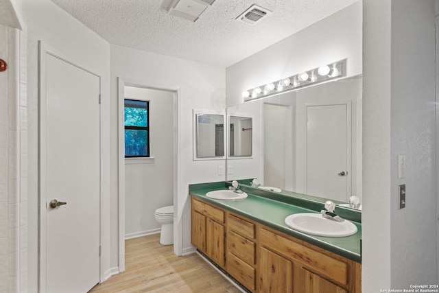 bathroom with a textured ceiling, hardwood / wood-style floors, vanity, and toilet