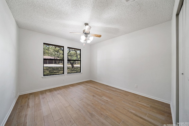 empty room with a textured ceiling, light hardwood / wood-style floors, and ceiling fan