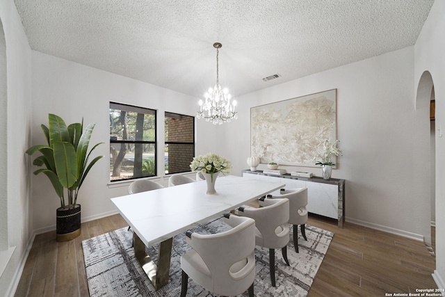 dining area featuring an inviting chandelier, a textured ceiling, and hardwood / wood-style flooring