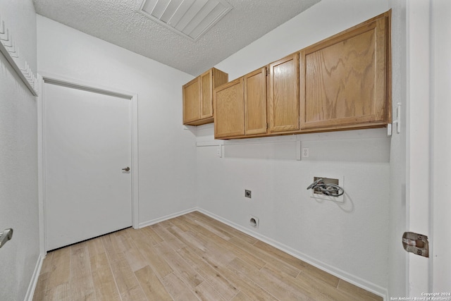 washroom featuring cabinets, light wood-type flooring, a textured ceiling, electric dryer hookup, and hookup for a washing machine