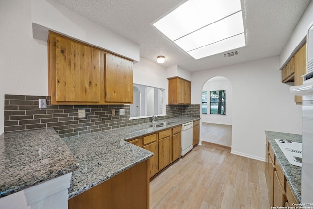 kitchen featuring a textured ceiling, light hardwood / wood-style flooring, backsplash, and white appliances