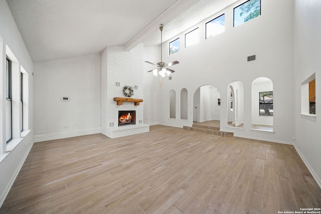 unfurnished living room with light hardwood / wood-style flooring, a wealth of natural light, and high vaulted ceiling