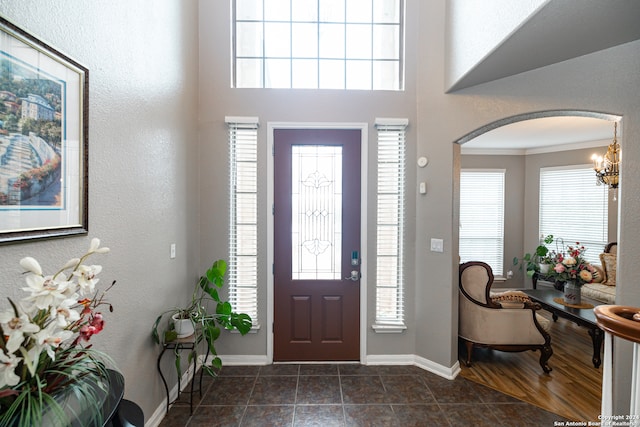 tiled foyer entrance with a chandelier and ornamental molding