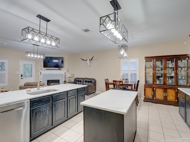 kitchen with hanging light fixtures, sink, a kitchen island, a brick fireplace, and dishwasher