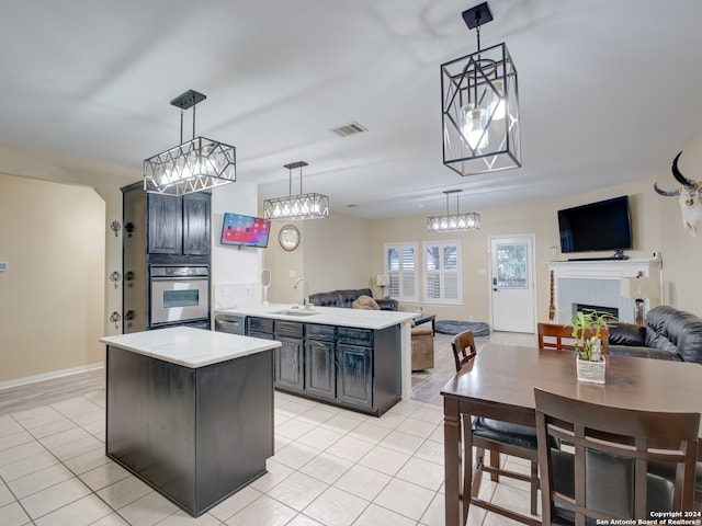 kitchen with oven, a center island, hanging light fixtures, and a fireplace