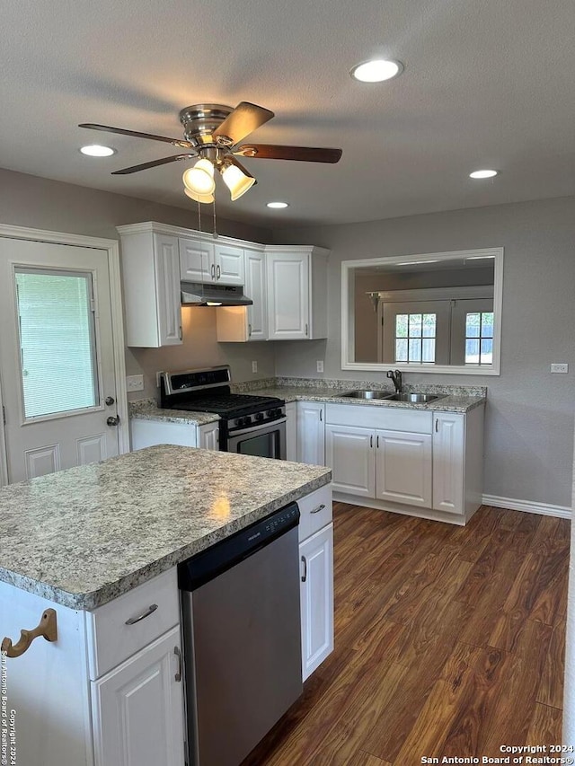 1505 B St, Floresville, TX 78114 - kitchen with stainless steel appliances, under cabinet range hood, a sink, dark wood-style floors, and white cabinetry