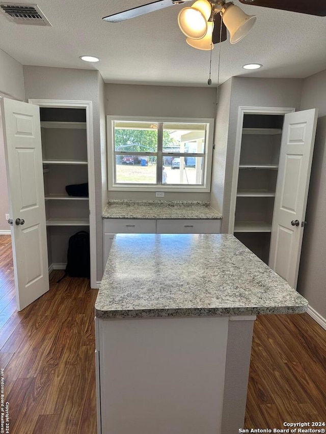 1505 B St, Floresville, TX 78114 - kitchen featuring a ceiling fan, dark wood-style flooring, a kitchen island, a textured ceiling, and light stone countertops