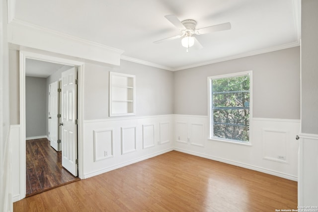 empty room with crown molding, ceiling fan, wood-type flooring, and built in features