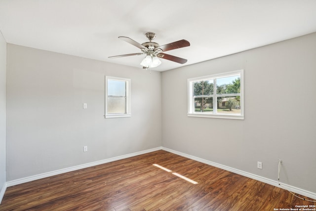 spare room featuring ceiling fan, a wealth of natural light, and dark hardwood / wood-style flooring