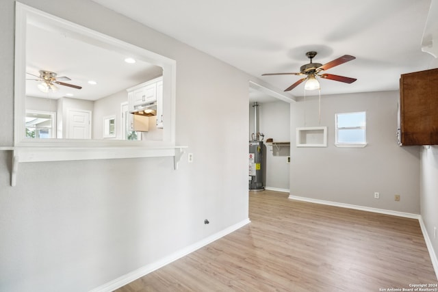 unfurnished room featuring ceiling fan, light wood-type flooring, and gas water heater