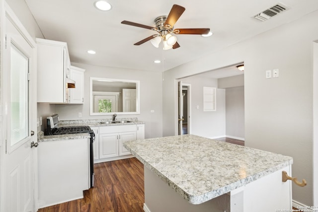 kitchen with sink, stainless steel gas stove, white cabinetry, dark hardwood / wood-style floors, and a kitchen island