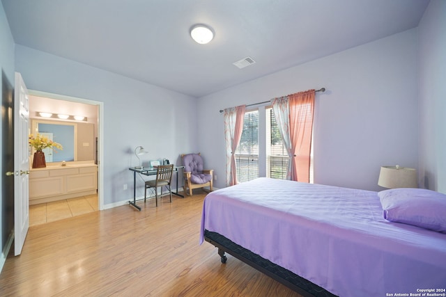 bedroom with light hardwood / wood-style flooring and ensuite bathroom