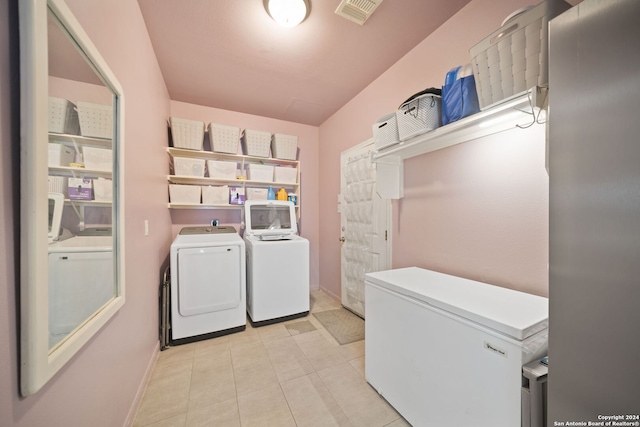 laundry area with light tile patterned flooring and washer and dryer