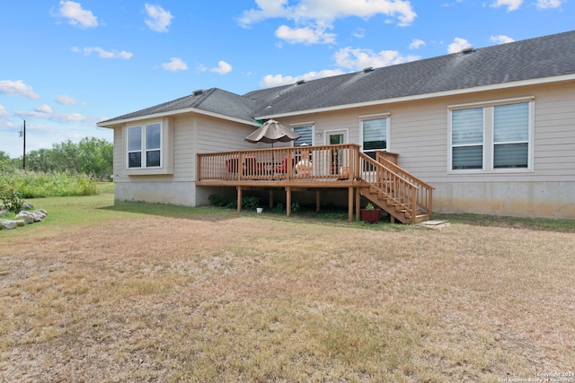 rear view of property with a wooden deck and a lawn