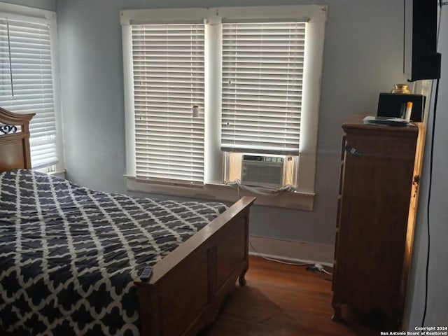 bedroom featuring multiple windows, cooling unit, and dark hardwood / wood-style floors