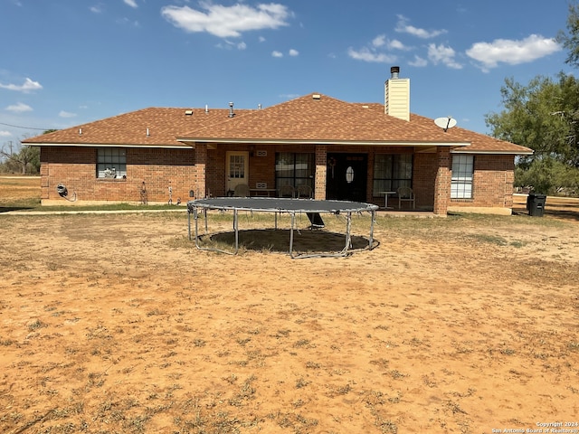 rear view of property featuring a trampoline