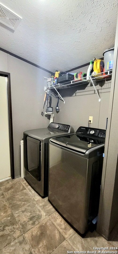 washroom with a textured ceiling and washer and clothes dryer