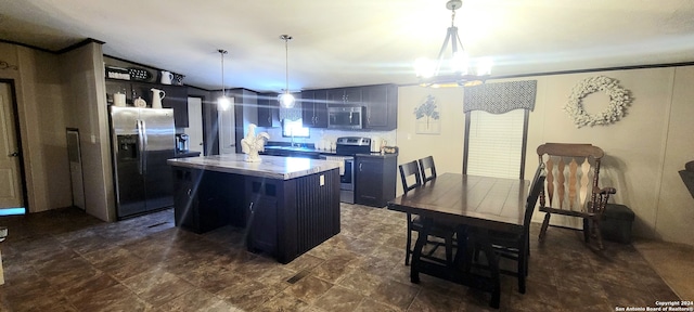 kitchen featuring a kitchen island, a chandelier, appliances with stainless steel finishes, decorative light fixtures, and a kitchen breakfast bar