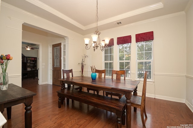 dining space with dark hardwood / wood-style floors, ceiling fan with notable chandelier, decorative columns, a raised ceiling, and ornamental molding