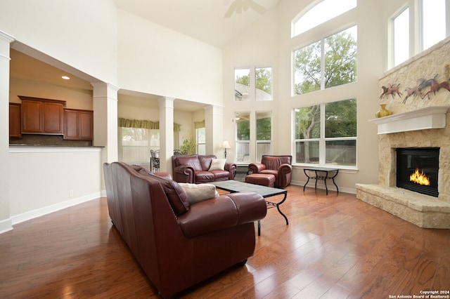 living room featuring ornate columns, a towering ceiling, ceiling fan, and dark hardwood / wood-style flooring