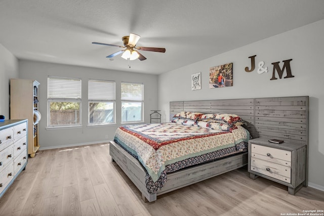 bedroom featuring light hardwood / wood-style flooring, ceiling fan, and a textured ceiling