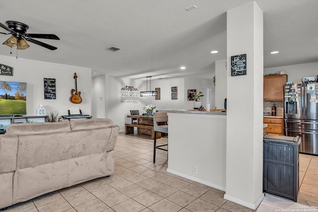 tiled living room with ceiling fan and a textured ceiling