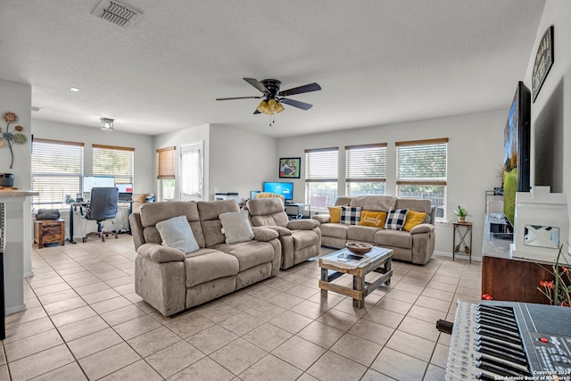 tiled living room featuring a textured ceiling, ceiling fan, and a wealth of natural light