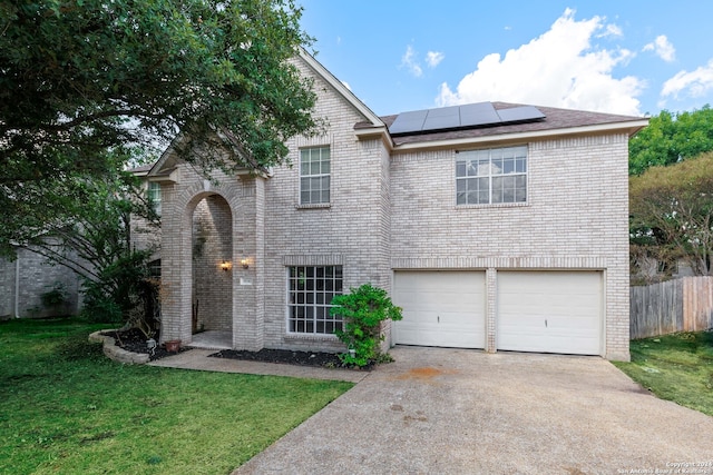 view of front of property with a garage, solar panels, and a front lawn