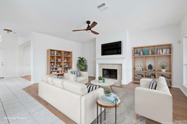 living room featuring ceiling fan, a fireplace, and light hardwood / wood-style flooring