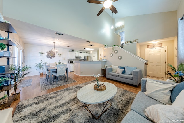 living room with light hardwood / wood-style flooring, high vaulted ceiling, and ceiling fan