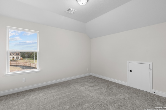 carpeted spare room with lofted ceiling